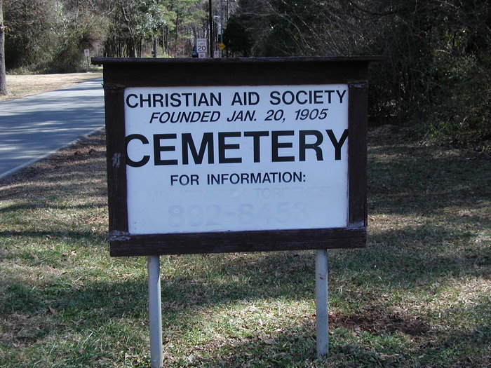 Wooden outdoor sign with black letter of the name of the cemetery on a white background.